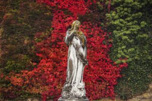 Feuerrotes Herbstlaub, Weinranken geben der Statue einen perfekten Hintergrund